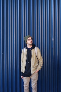 a young man standing in front of a blue wall