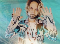 a man with long hair and a beard is posing with his hands up